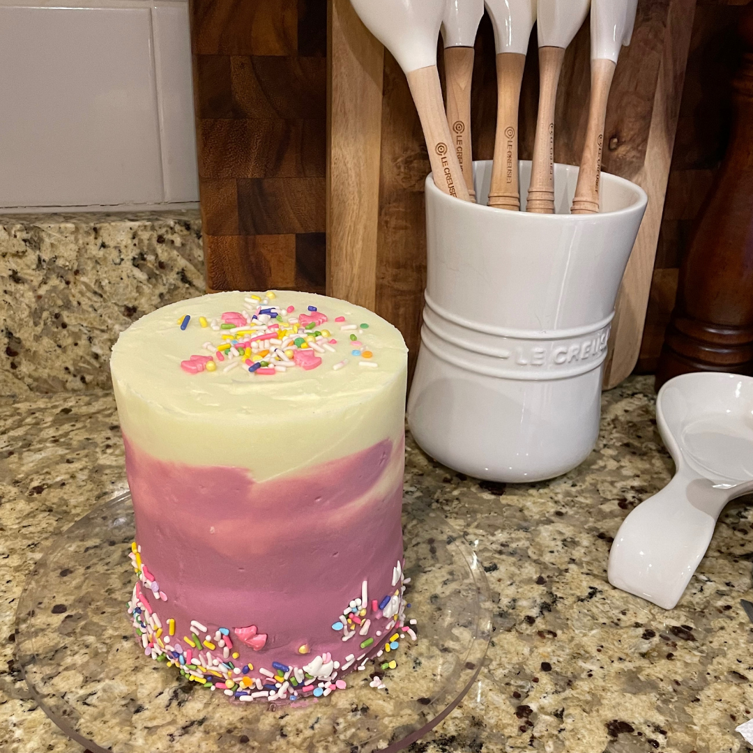 Small pink and cream buttercream cake with colorful sprinkles