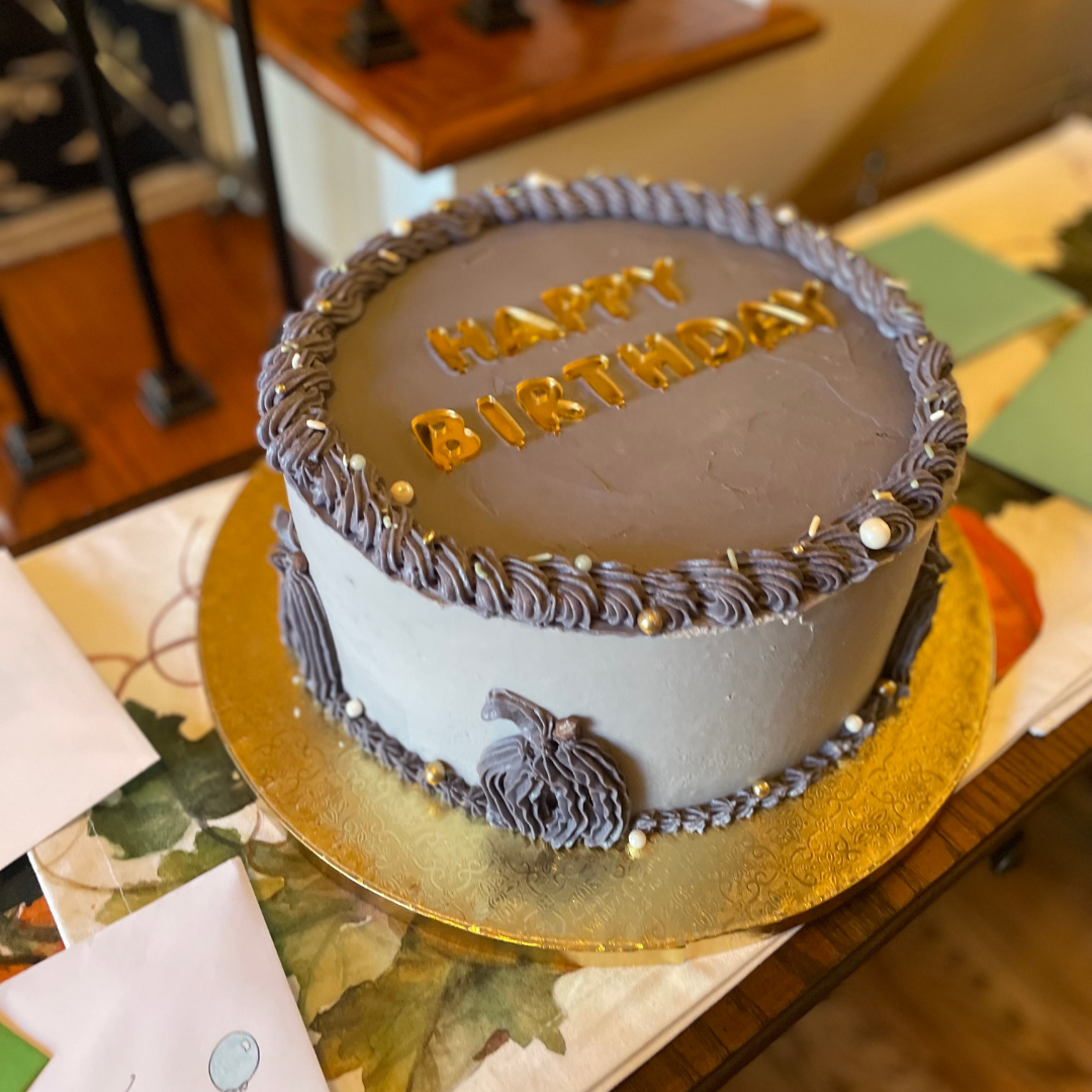 Gray-blue buttercream birthday cake with piped pumpkins and gold lettering.