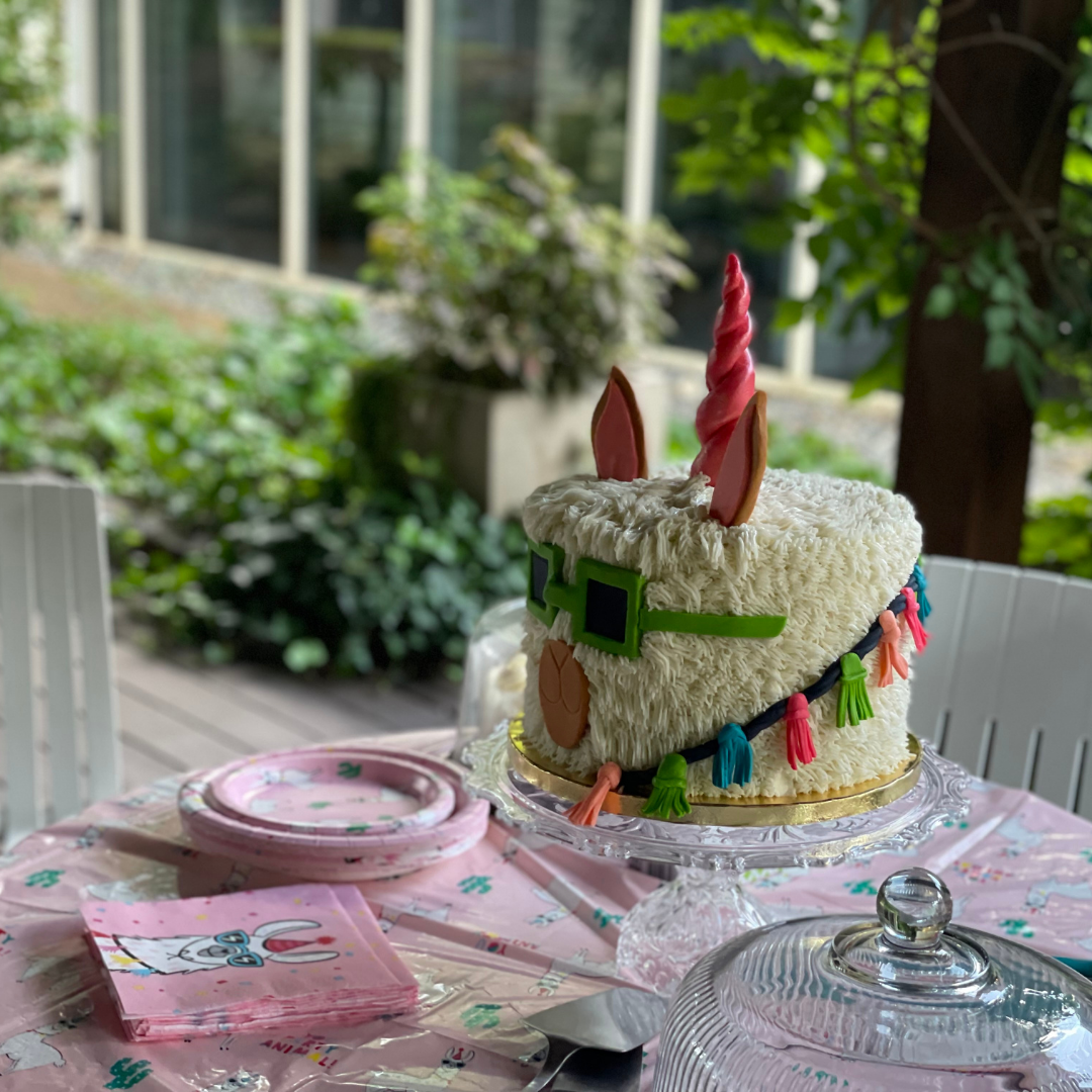 Llama unicorn cake with tassels and sunglasses viewed from the side.