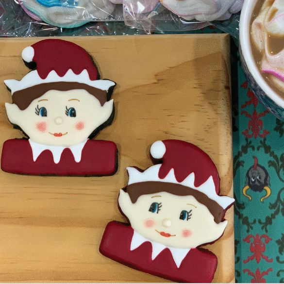 Royal icing cookies decorated as playful Elf on the Shelf characters in festive red and white details.